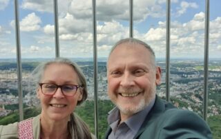 Claudia Schimkowski und Thomas Issler lächeln in die Kamera, im Hintergrund der Blick über Stuttgart