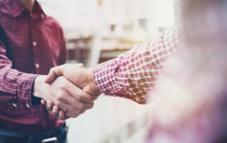 Zwei Männer in karierten Hemden geben sich die Hand