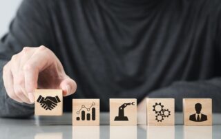 Holzwürfel mit Symbolen für Partnerschaft, Wachstum, Technik, Prozesse und Führung