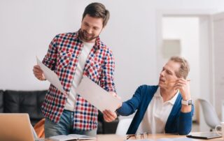 Zwei Männer besprechen Pläne an einem Schreibtisch